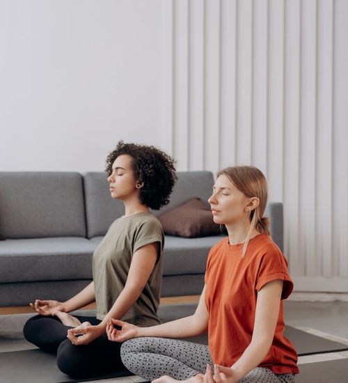 Woman performing a calm yoga pose in a bright, minimalist room.